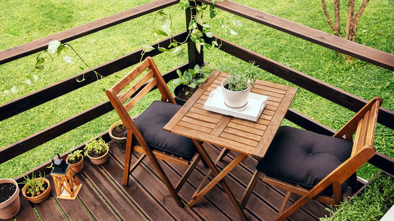 wooden outdoor table between outdoor wooden chairs with cushion