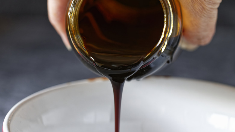 hand pouring molasses into a white bowl