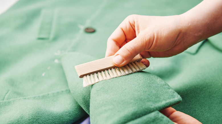 Close up of person brushing green coat