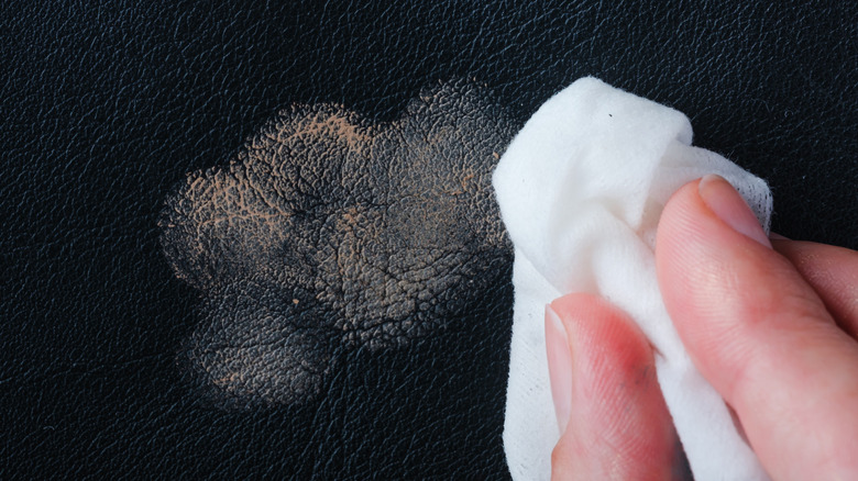 Close up of person wiping stain off leather jacket