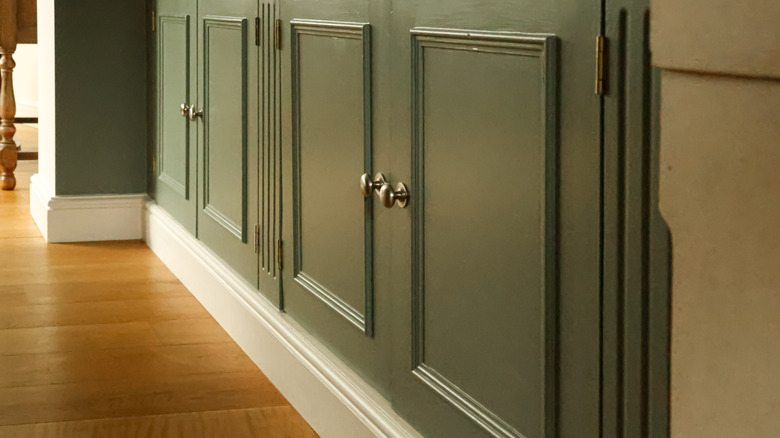 Close-up of green painted kitchen cabinets with chrome knobs