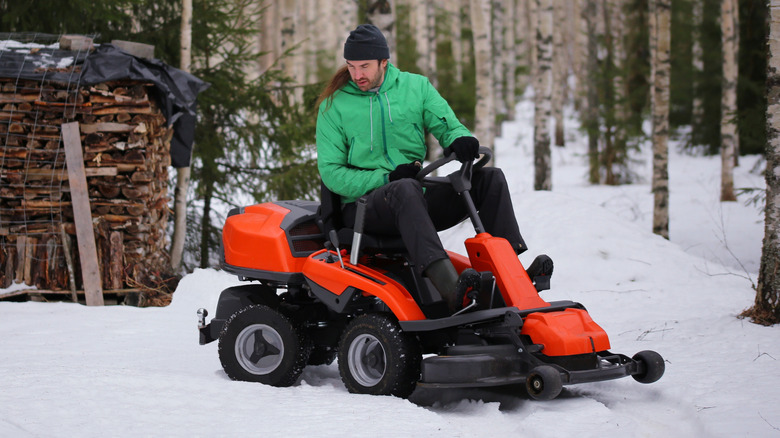 A man driving a lawn mower across a snow-covered yard