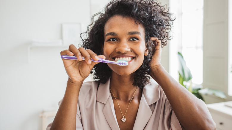 Dressed up woman brushing teeth