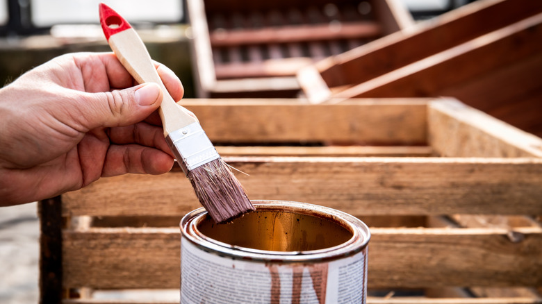 close-up of someone soaking a paintbrush in wood stain