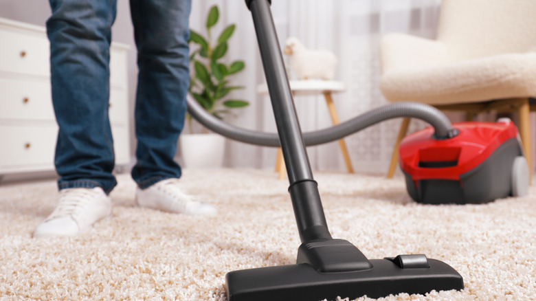 close-up shot of a man vacuuming a carpet