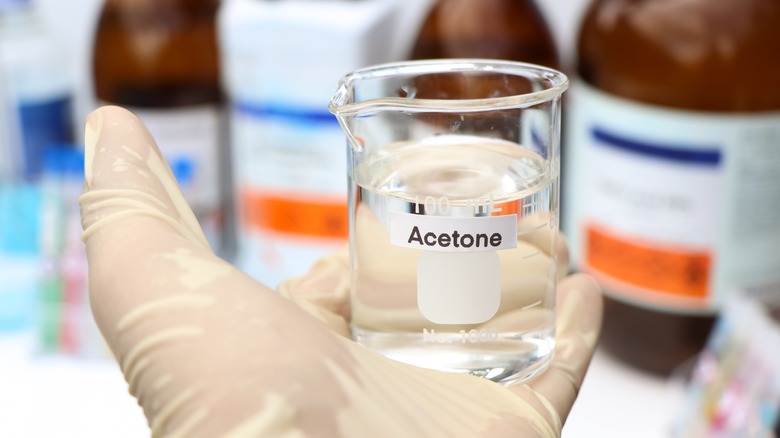 Gloved person holding acetone glass