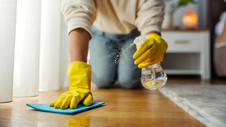 Close-up of a person spraying and wiping a wood floor