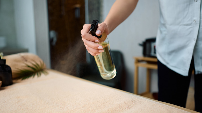 a person spraying aromatic oil on a table
