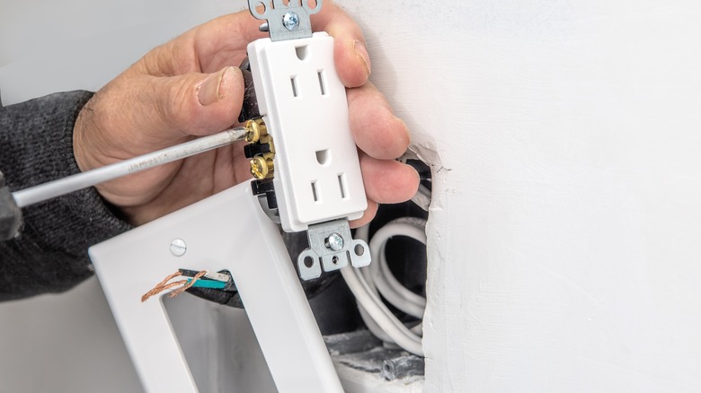 person installing an electrical outlet