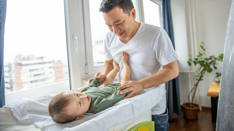 father changing son's diaper