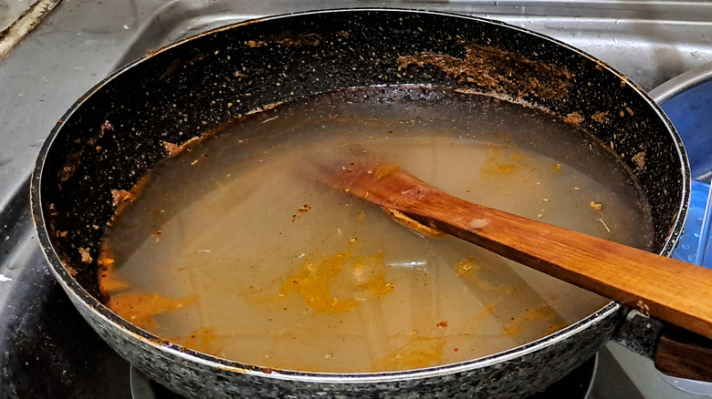 Pan with residue from cooking in a sink