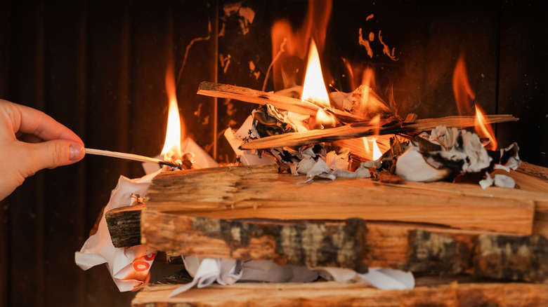 Person lighting a fireplace with a match