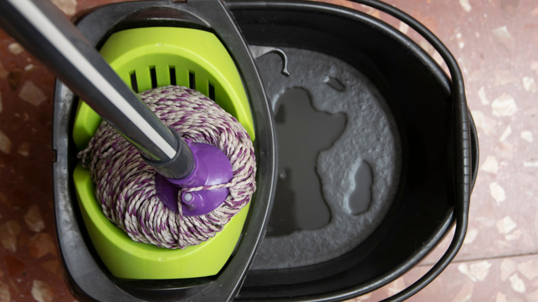 A bucket and mop set on terrazzp tile floors.
