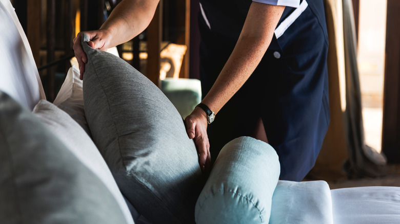 person fluffing couch cushion