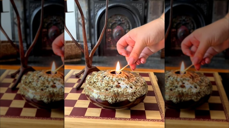 Closeup of person's hand lighting incense in a flower frog vase