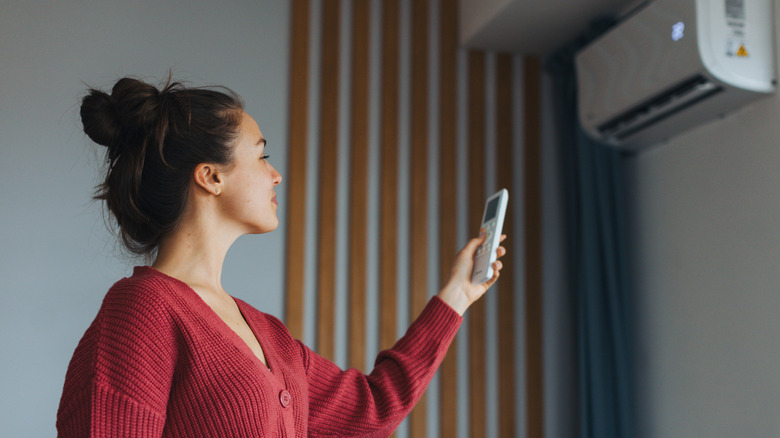 Woman adjusting AC temperature with remote control
