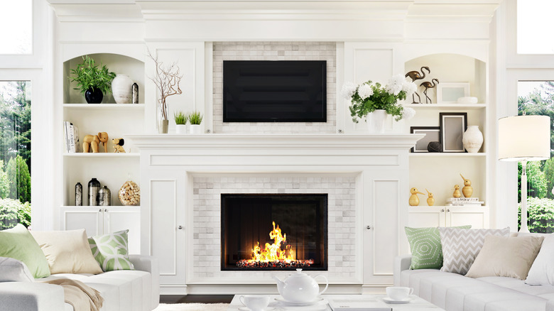 Living room with a TV safely mounted above a fireplace in a white, modern living room
