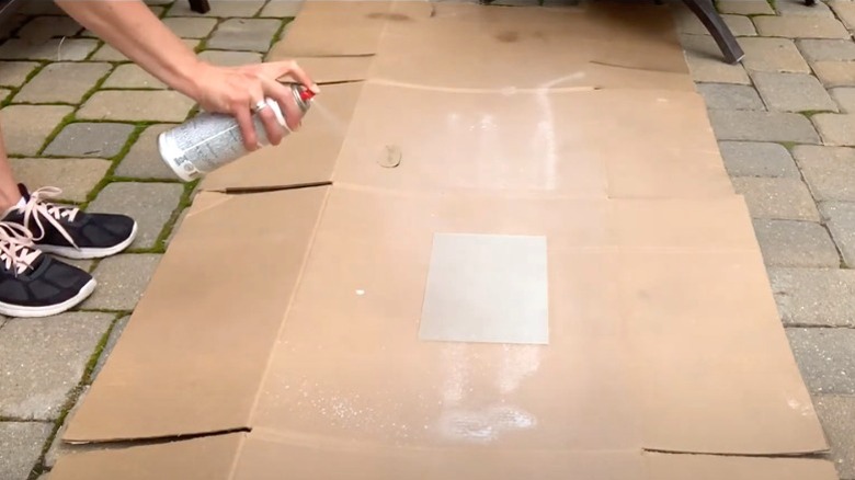 person spraying small glass panel with frosted glass spray paint on patio