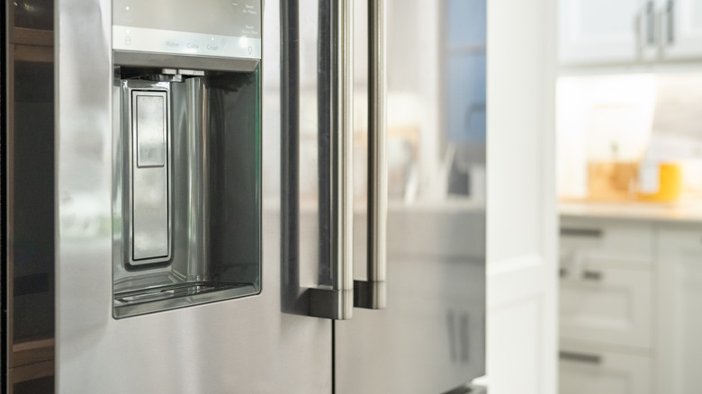 Ice dispenser in door of stainless steel refrigerator.