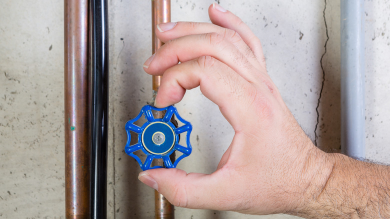 Hand turning off water on copper pipe