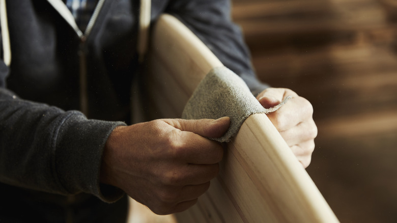 Hands sanding curved edge of wood