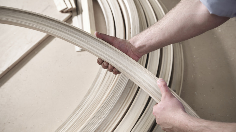 hands holding curved piece of wood