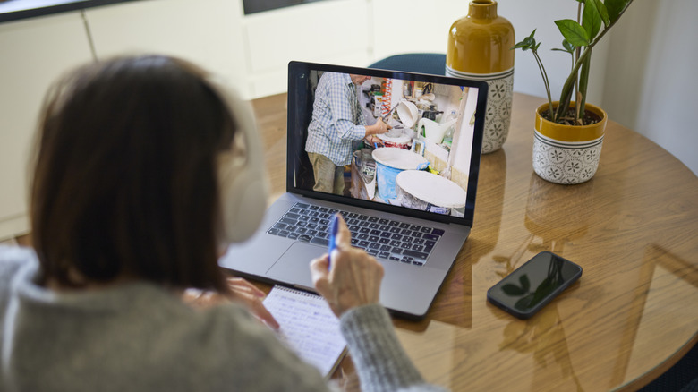 Woman at wooden table taking notes on laptop video