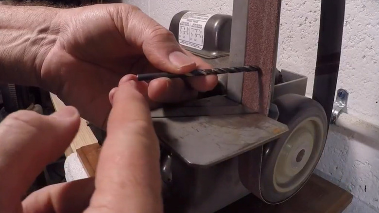 Hands demonstrating how to sharpen drill bit