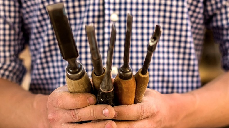 A person holding a collection of woodworking tools