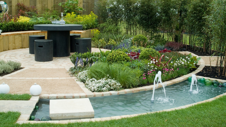 A water feature nearby a seating area in a backyard garden.