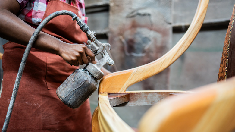 A carpenter painting a chair in a workshop