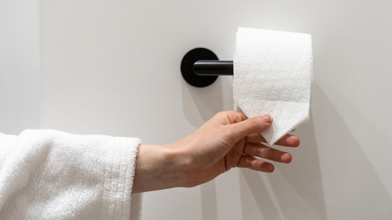 hand grabbing folded toilet paper