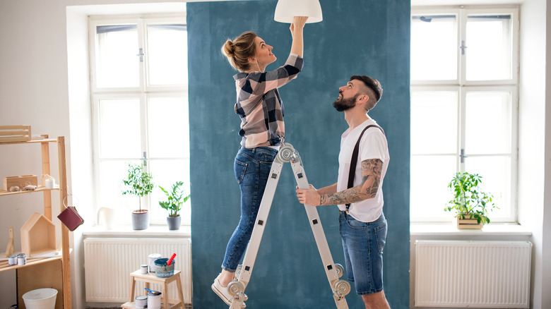 couple changing lightbulb in home