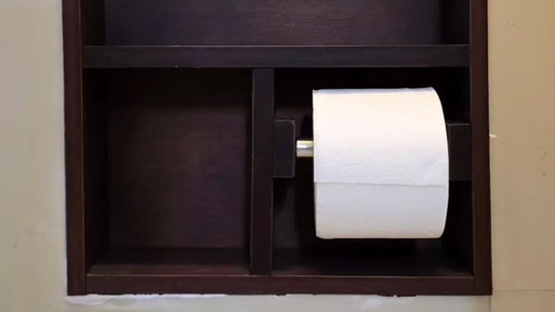 A toilet paper roll in a built-in cabinet