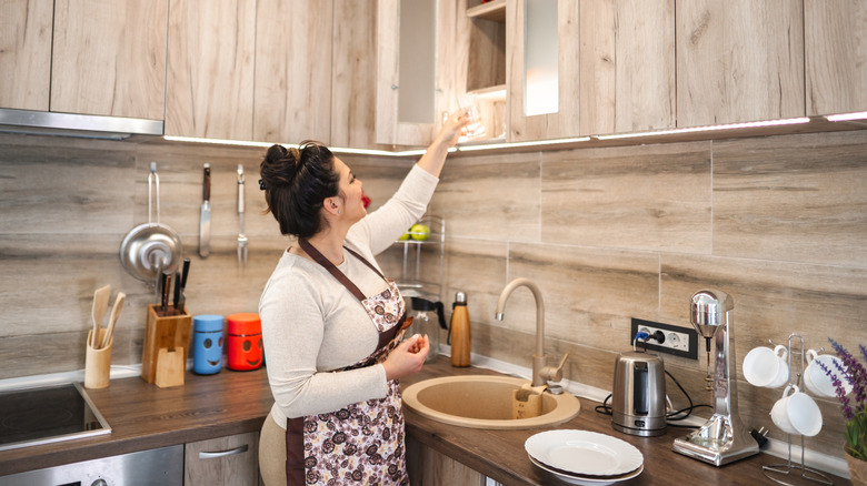 A person removing items from an overhead cabinet
