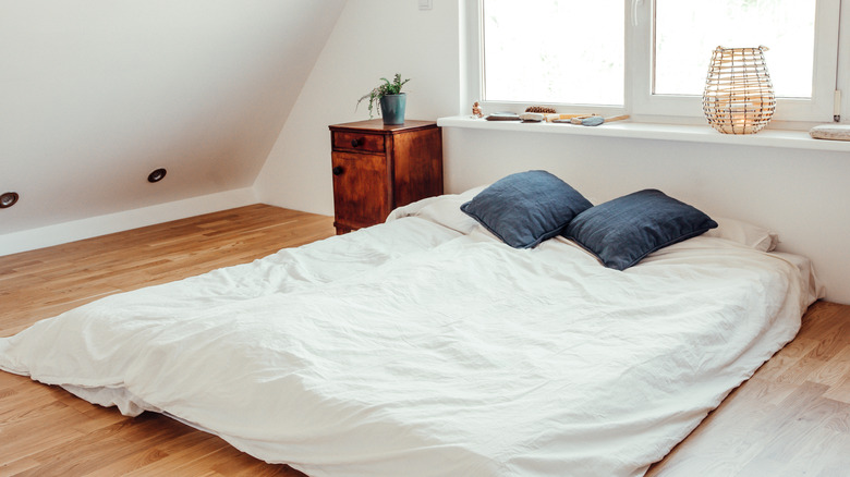 A basic floor mattress with white bedding.