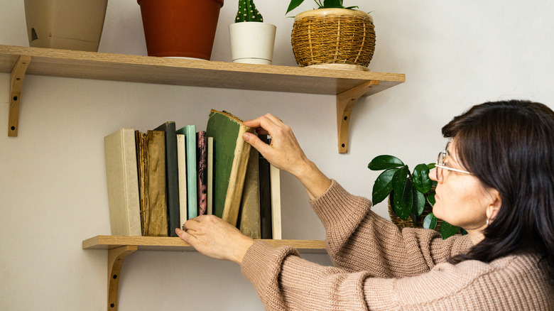 Woman taking book from shelf
