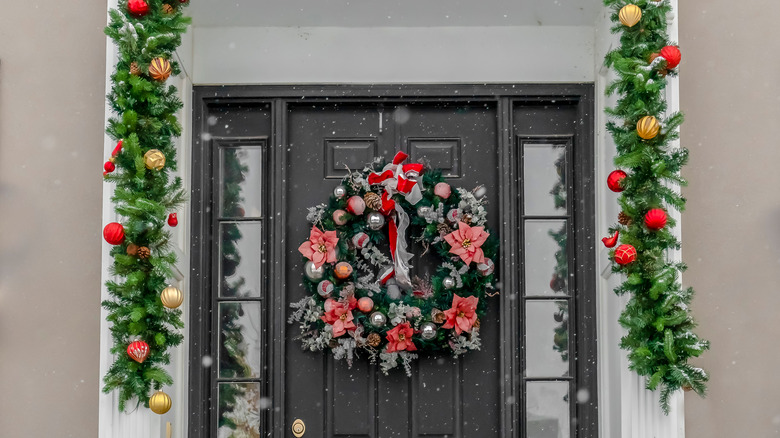A house entranceway with bright green garland hanging to halfway down the door