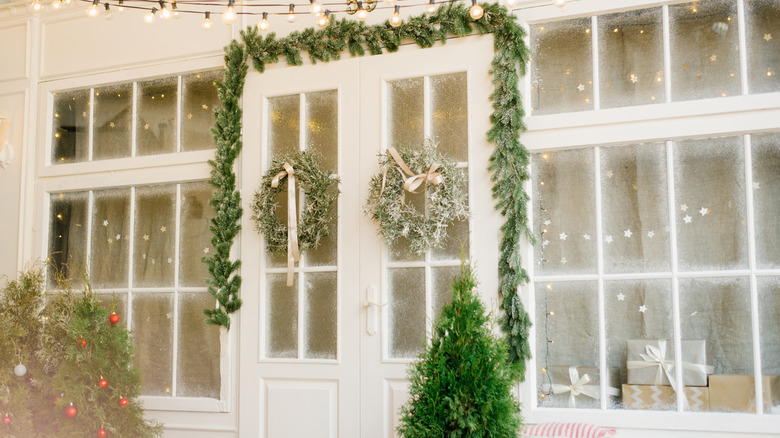 A white building with garland around the doors and frosted windows