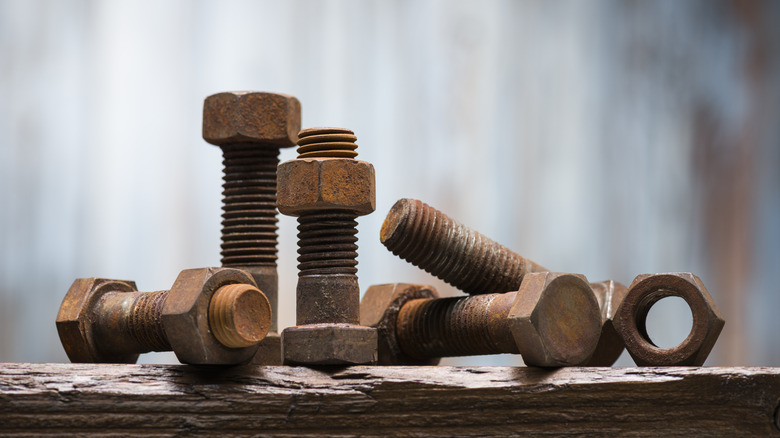 rusted bolts and nuts on a piece of wood