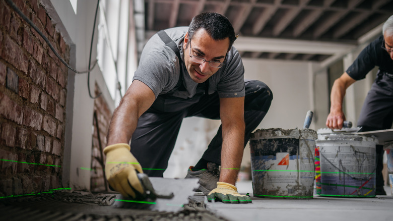 Man installing a tile floor over concrete