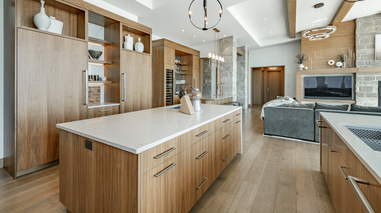 A wide shot of a modern kitchen and living room with island and wooden floors