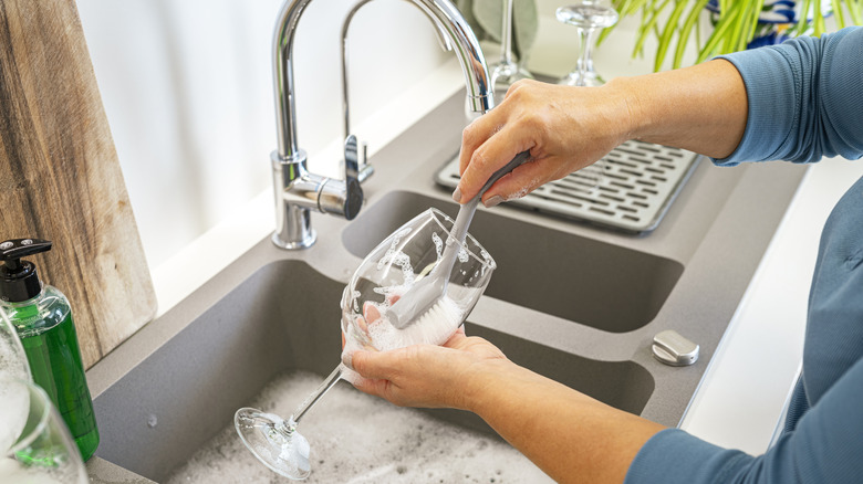 Woman cleaning a wine glass at the kitchen sink