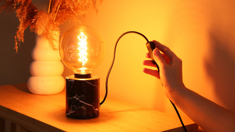 person switching on a table lamp
