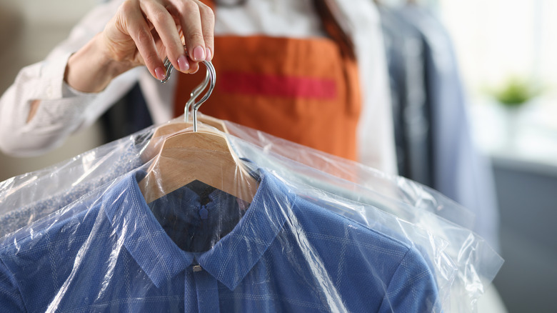 Person holding dry-cleaned clothes