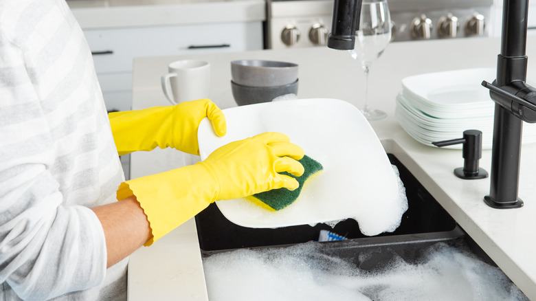 person washing dishes with sponge