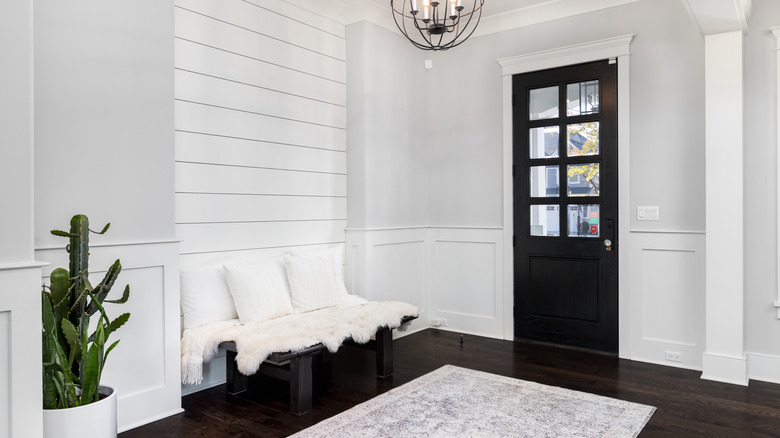 An entryway with dark wood flooring and a white shiplap accent wall