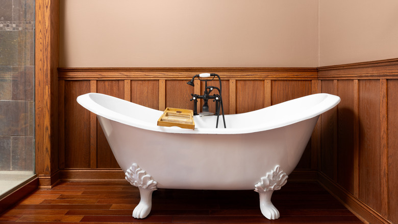 Vintage wood paneling behind a clawfoot bathtub