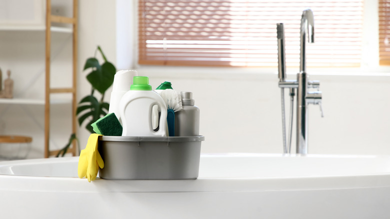cleaning caddy on the side of a bathtub with various cleaning products