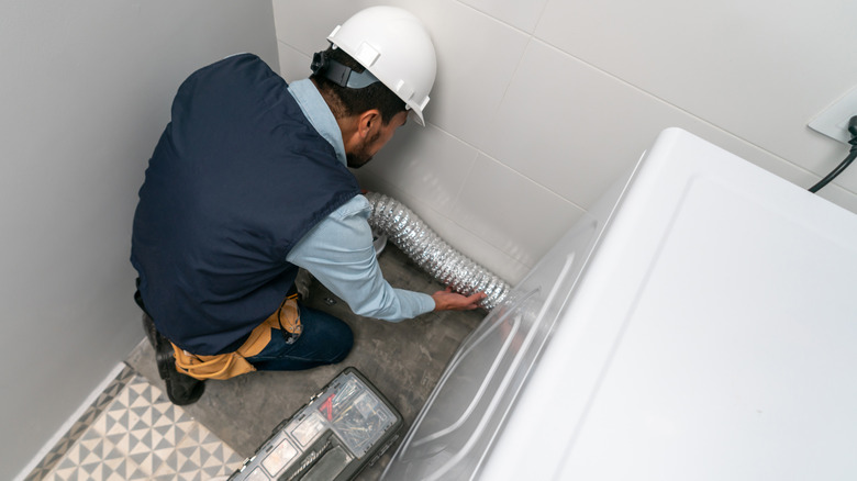technician inspecting a dryer machine at a house